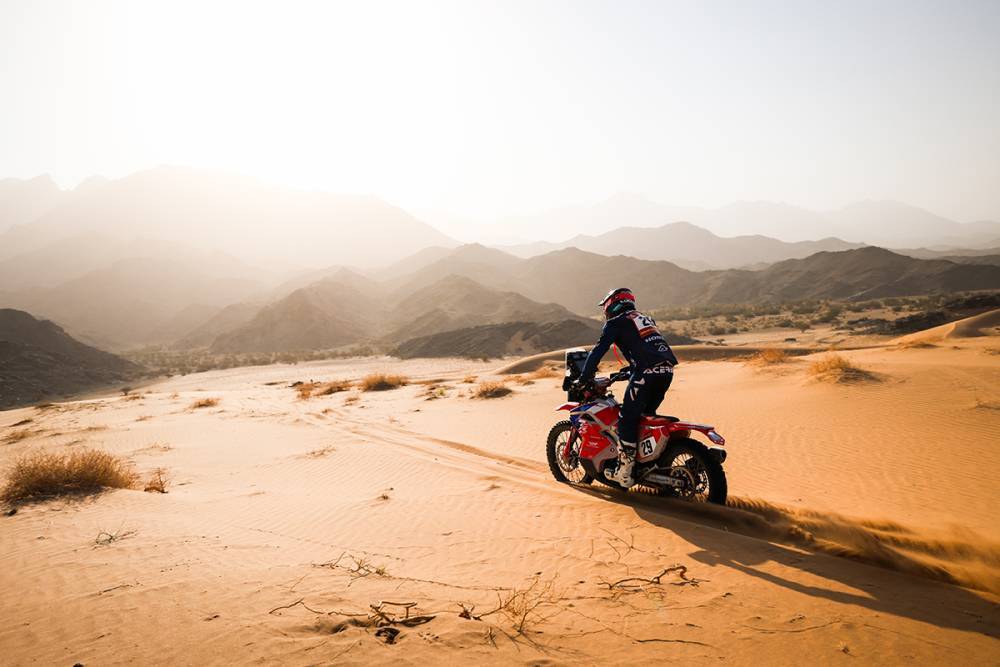 Сервисен шатор на TimeOut Racing осветлен ноќе во бивакот на Dakar Classic, со возила на натпреварувачи и камиони за асистенција